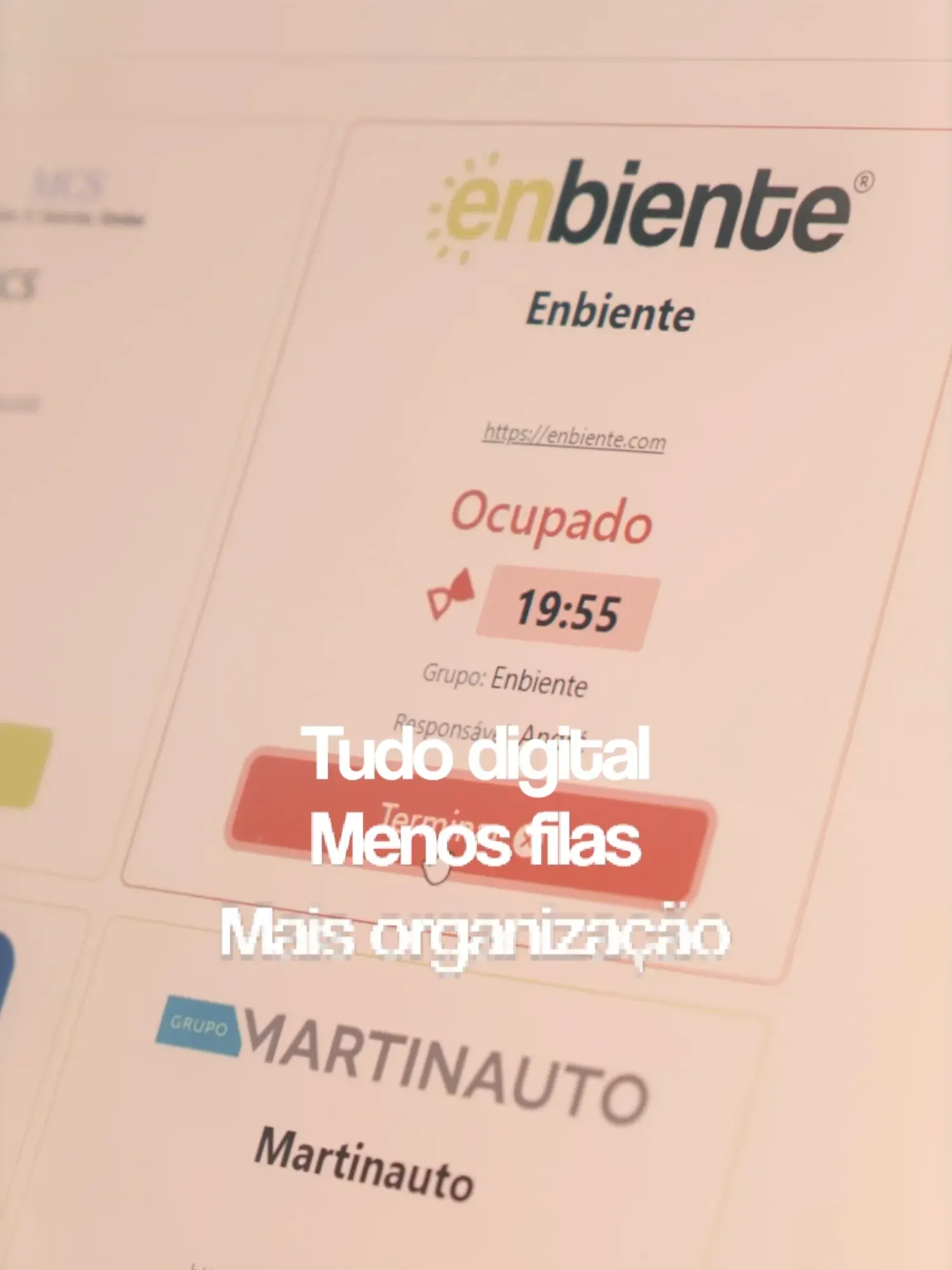 Um fotograma do vídeo: o ecrã da app no stand da Enbiente, marcado como Ocupado com um cronómetro (19:55), o grupo responsável e o botão para terminar, e outros stands por baixo. Sobreposto, o texto: tudo digital, menos filas, mais organização.